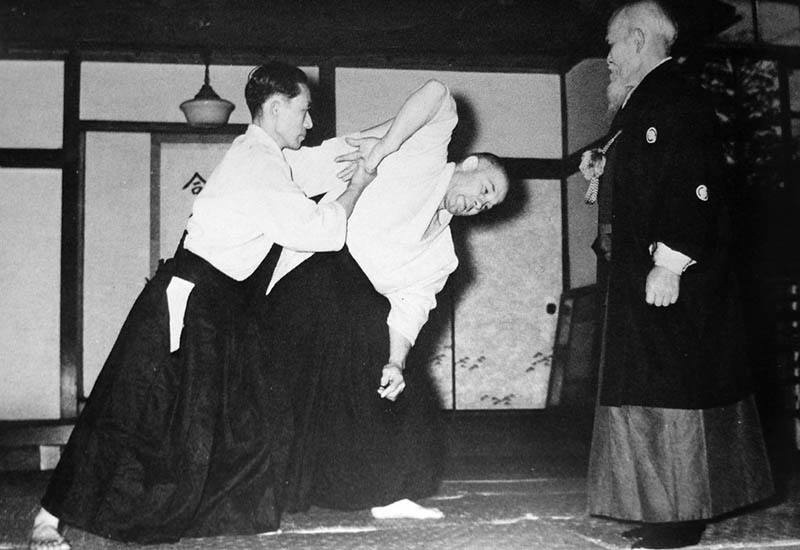 О-Сенсей наблюдает за исполнением техники своим сыном, Киссемару Уэсиба (2-й Дошу)