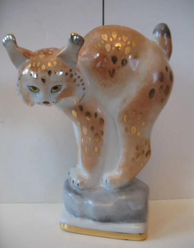 "Молодая рысь" ("Рысёнок"). Модель 1954-го года. Размеры: 22,0*16,5*9,0 см. Зверь стоит на бугорке (или камень, или снег). Нижний постамент низкий четырехугольный, по по нижнему краю золотая кайма. Фото взято из свободного доступа в интернете.
