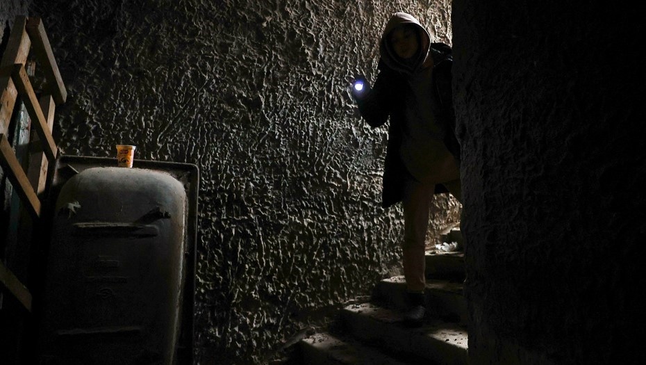    Женщина спускается в подвал с фонариком. Автор фото: Михаил Терещенко / ТАСС