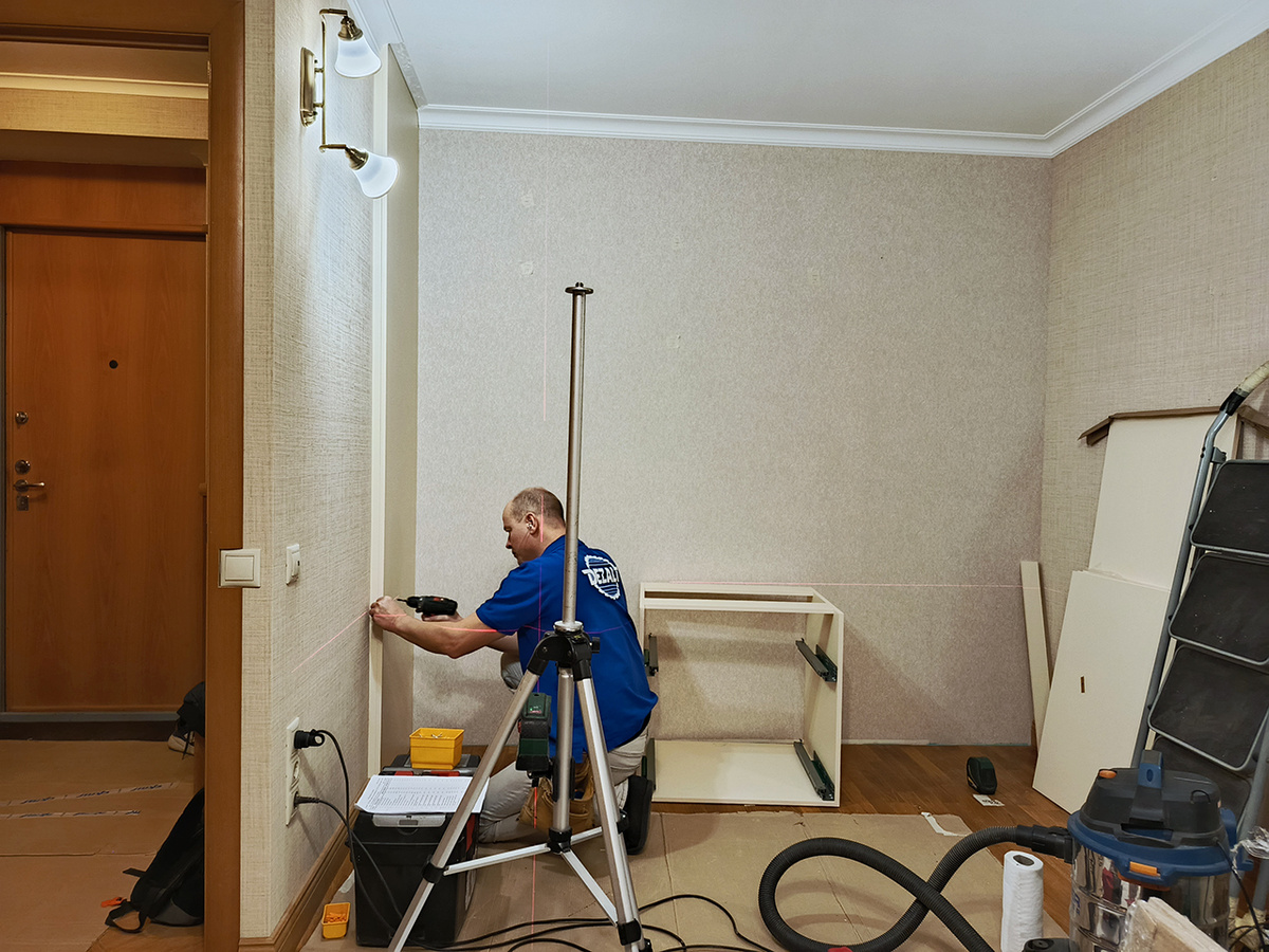 Григорий ставит первую планку, крепит к стене. Она нужна чтобы двери не заминали плинтус напольный. 