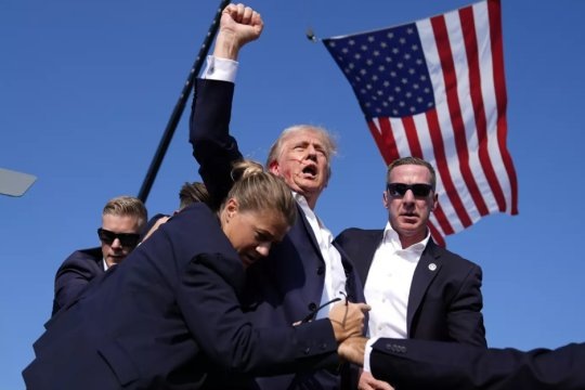 Дональд Трамп и его охрана спустя мгновения после того, как пуля «поразила» его право ухо во время предвыборного выступления летом 2024 года. Фото: Ассошиэйтед Пресс