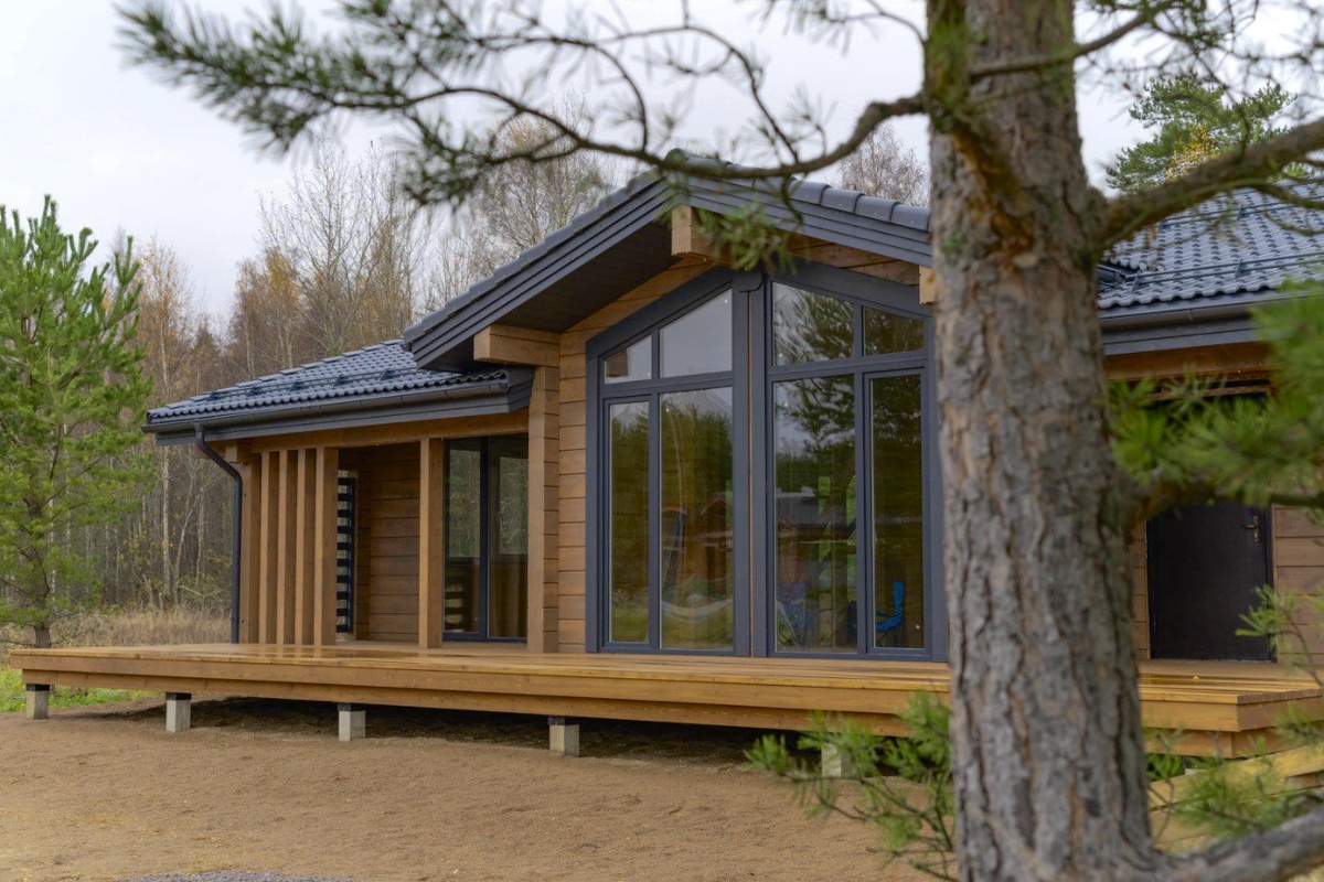 Дом из клееного бруса, покрытого натуральным фасадным маслом, идеально вписывается в лесной пейзаж