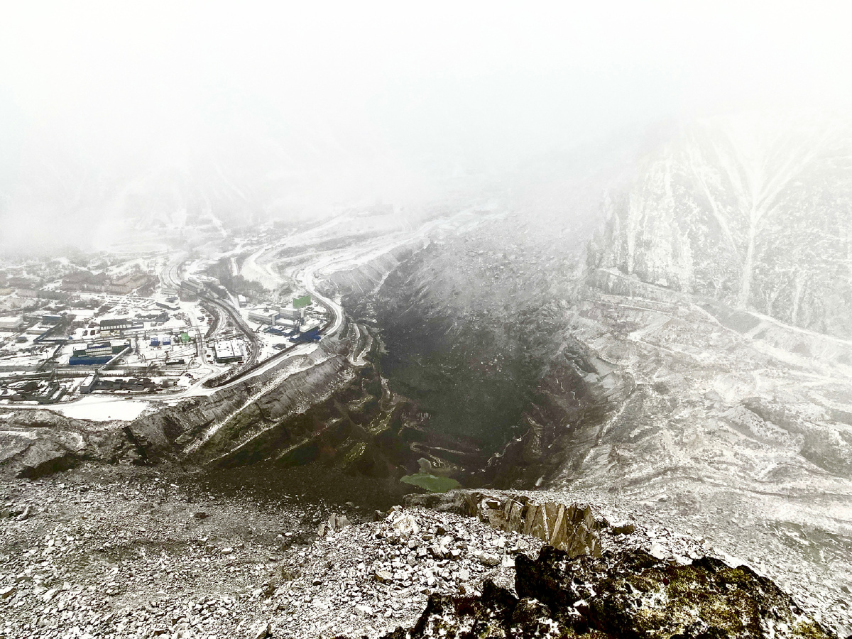 Карьер Кировского рудника. В дальней его части - отвалы пустой породы, которой его засыпают