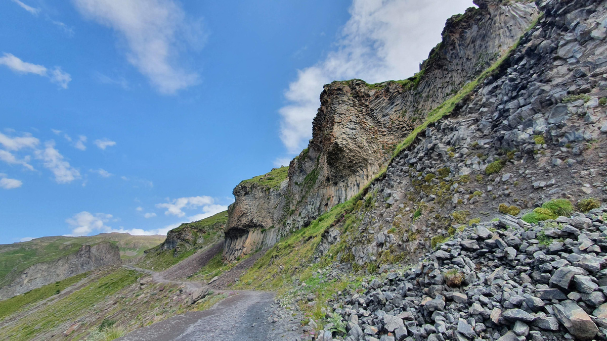 Август 2021г. Дорога после выхода из леса, до водопада осталось уже немного. Справа над дорогой нависают скалы из застывшей магмы - история Эльбруса как активного вулкана.