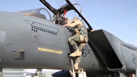 Пилот F-15E Strike Eagle взбирается в кабину по складной лестнице.