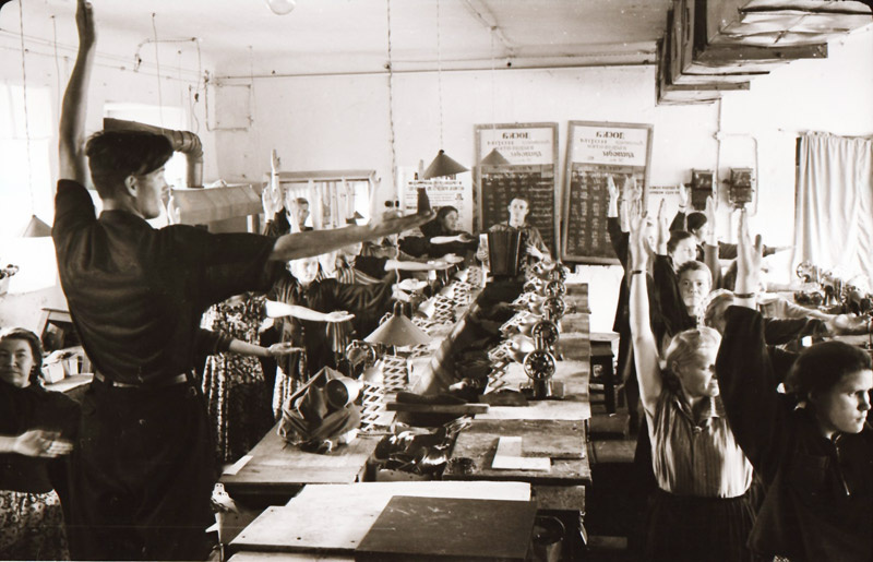 Работницы Кунгурской артели «Вперёд» выполняют гимнастику на рабочих местах под звуки аккордеона. Фотография датирована 1959 годом