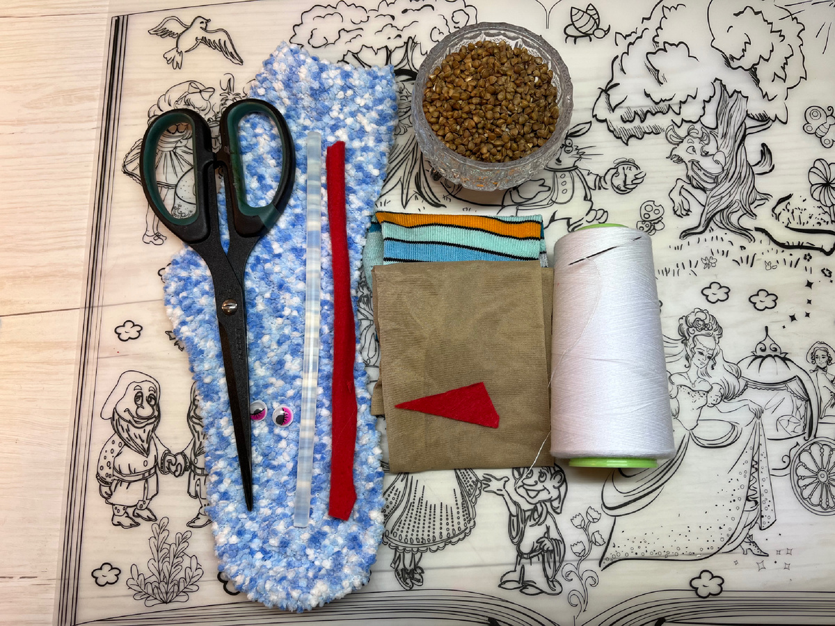 Нам понадобится: носок основа (желательно толстый, зимний), капроновый носок или колготки (если у вас основной носок, который будет для туловища, ажурный и в нем есть маленькие дырочки), иголка с ниткой, ножницы, кусочек фетра, глазки (не обязательно), клеевой пистолет, полоска ткани, ленты или пряжи для шарфа, носок или ткань для шапочки, гречка.