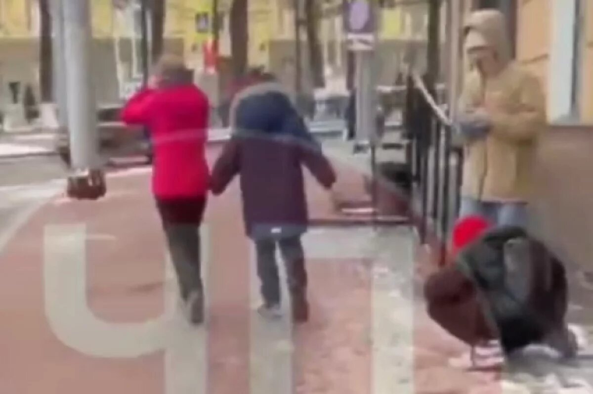    Кадр из видео: сидящий у стены мальчик и удаляющиеся женщина с сыном