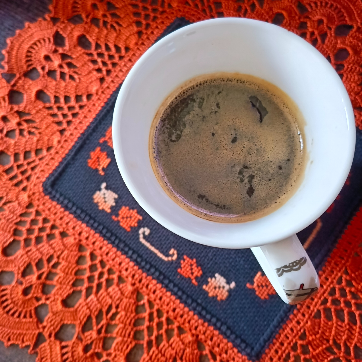 Чёрный кофе на чёрной салфетке в обрамлении королевского терракота ажурной каймы