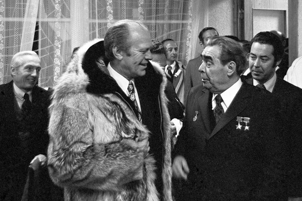 Президент Соединенных Штатов Америки Джеральд Рудольф Форд-младший в шубе из меха волка, подаренной ему на Аляске, Генеральный секретарь Центрального Комитета Коммунистической Партии Советского Союза Леонид Ильич Брежнев (слева направо на первом плане), Чрезвычайный и Полномочный Посол США в СССР Уолтер Джон Стессел-младший (слева на втором плане) и личный переводчик Л. И. Брежнева Виктор Михайлович Суходрев (справа на втором плане) во время вручения личной шубы Дж. Фордом Л. И. Брежневу в Доме переговоров на территории военного санатория «Океанский» во Владивостоке, 1974 год / Владимир Мусаэльян/ТАСС   📷