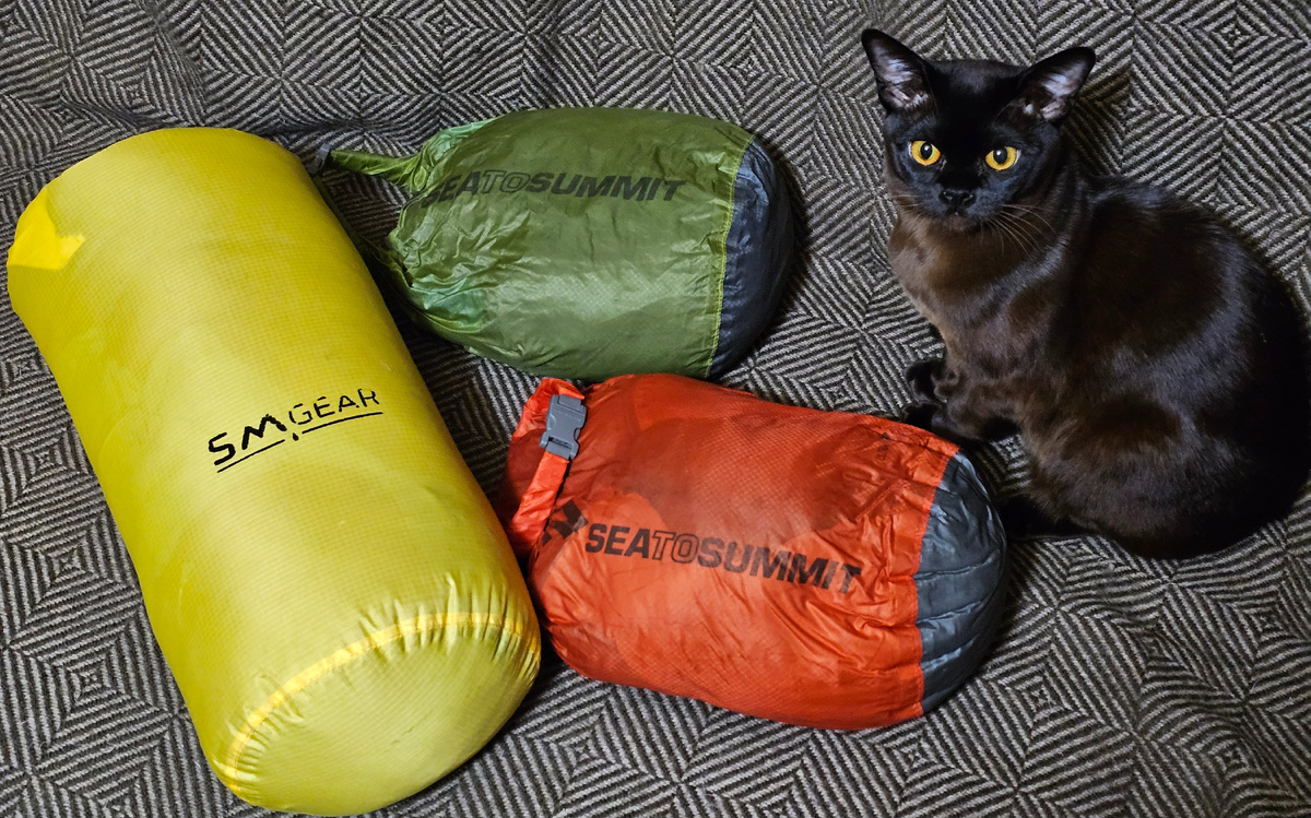 Спальники в гермомешках. Жёлтый - Marmot Plasma 15 (предел комфорта -9), красный - Сивера Вежа -1 (предел -1), зелёный - Сплав Antris 60 (предел +10). И котёнок Олаф для масштаба, куда без него..