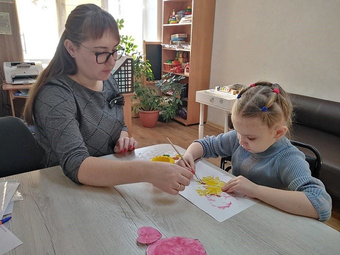 Девочка рисует кистью на бумаге под руководством Першиной Вероники Вячеславовны