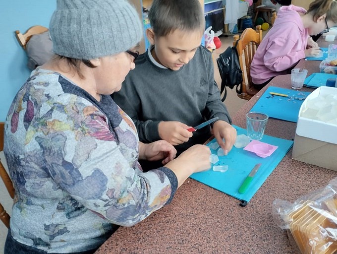 Мама помогает сыну нарезать ингредиенты для мыла