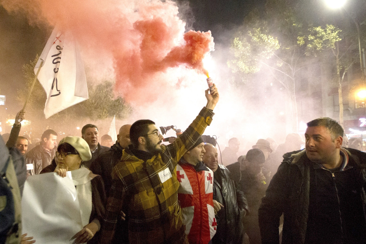 Демонстранты жгут файеры под стенами грузинского парламента на проспекте Руставели.
Фото: AP Photo