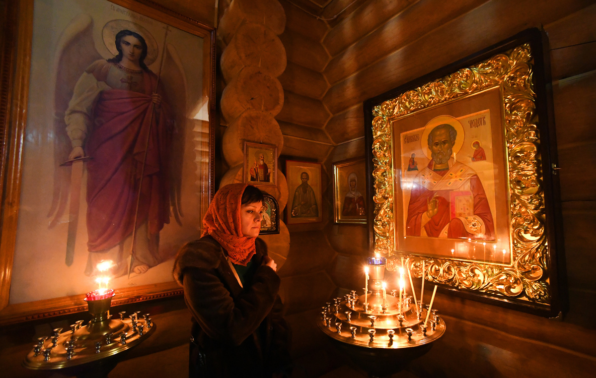     Прихожанка деревянной Знаменской православной церкви в Дивногорске (Красноярский край) во время Рождественской литургии / РИА Новости / Илья Наймушин