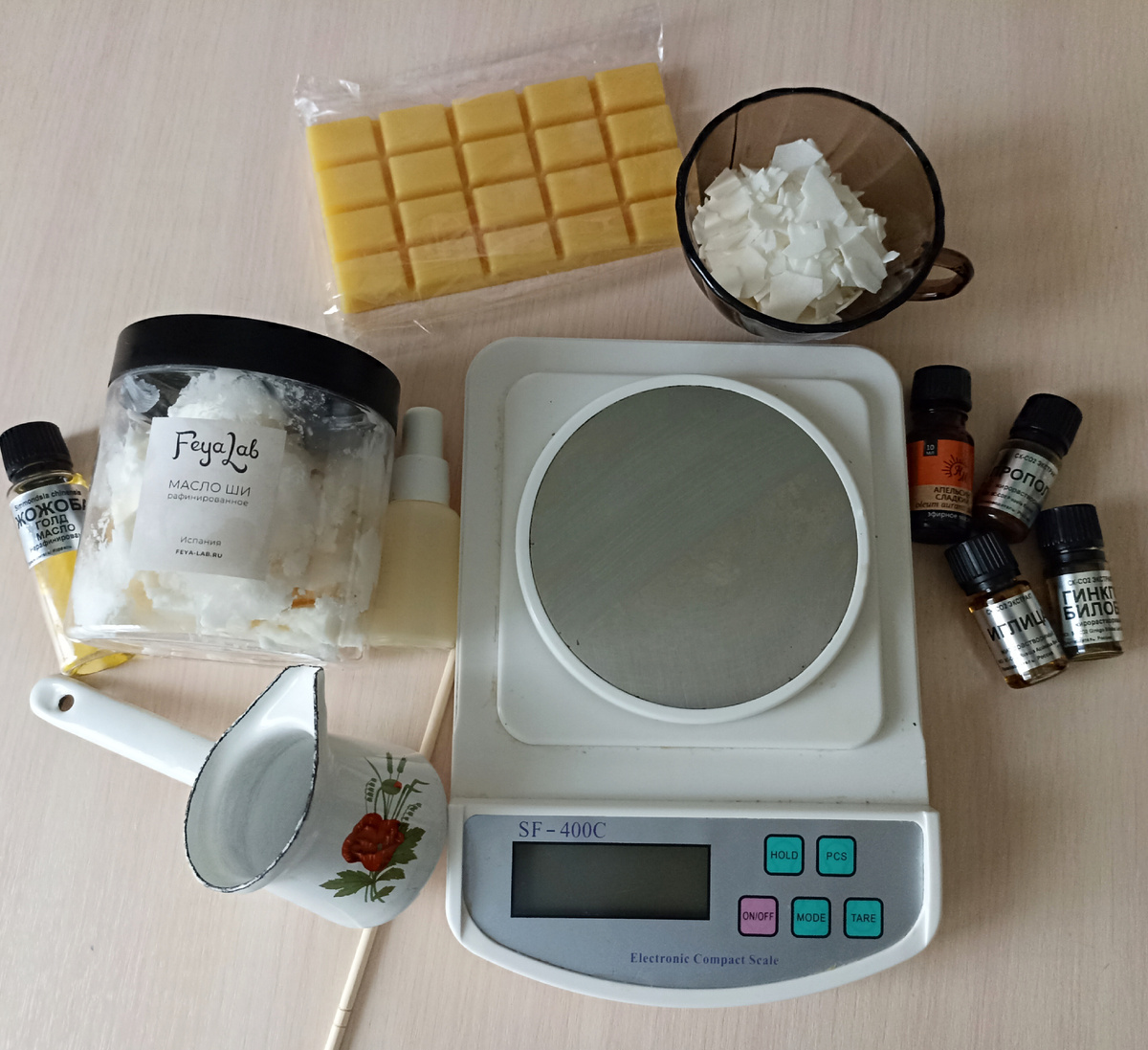 Желтая плитка- это пчелиный воск. Белые хлопья в чашке-это соевый воск. Безымянный флакон около весов-это витамин Е (не заметила что флакон перекатился и надпись спряталась).