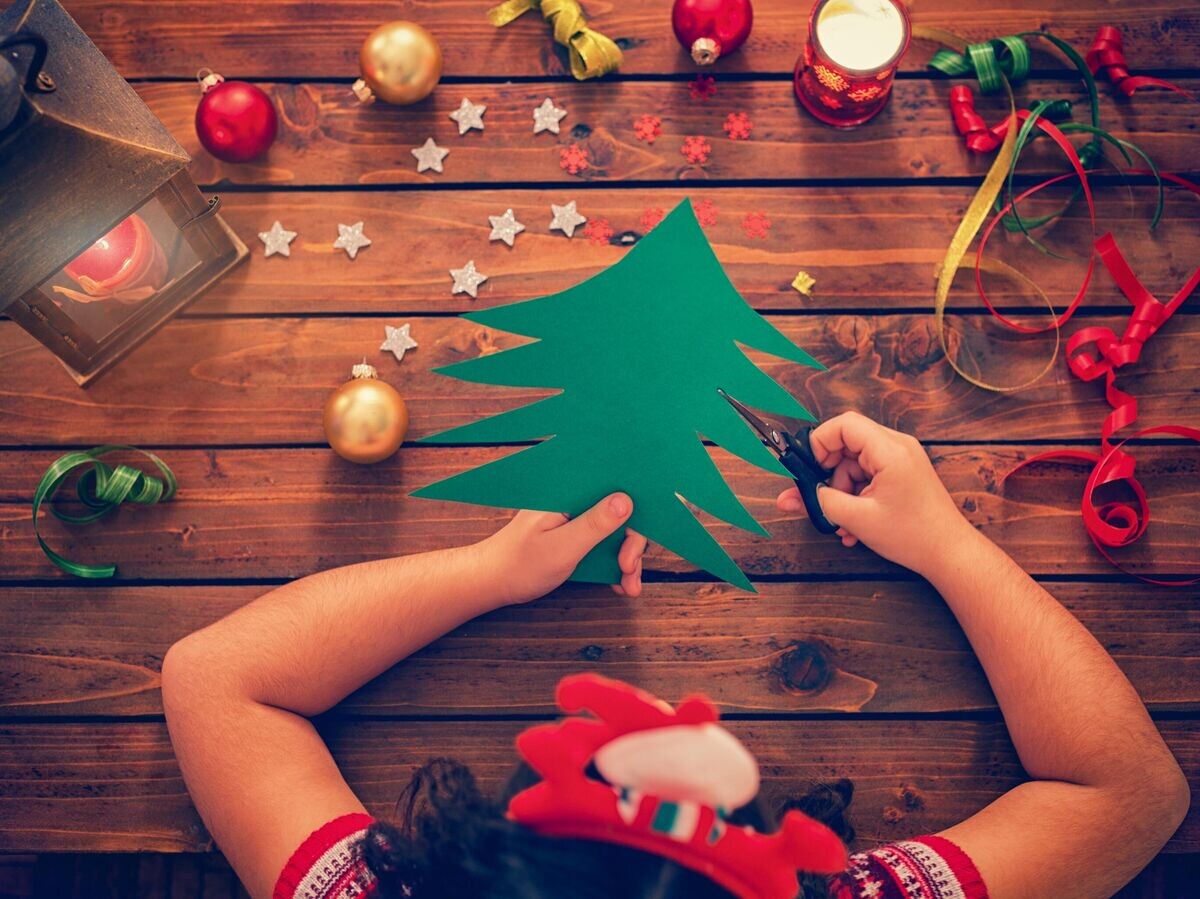    Ребенок вырезает елку из бумаги © iStock.com / kajakiki