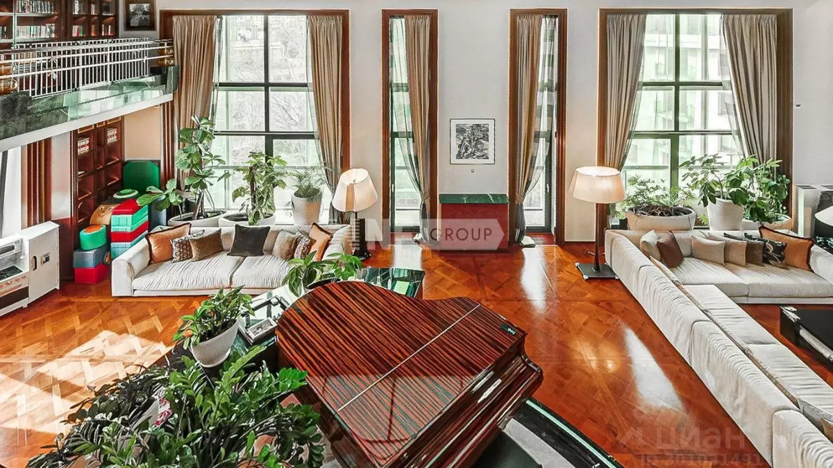 Рояль из красного дерева в окружении фикусов наполняет двухуровневую гостиную музыкой. Фото: ЦИАН