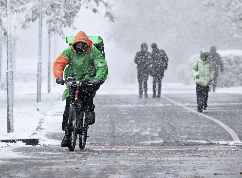 Курьер службы доставки во время снегопада на одной из улиц Москвы