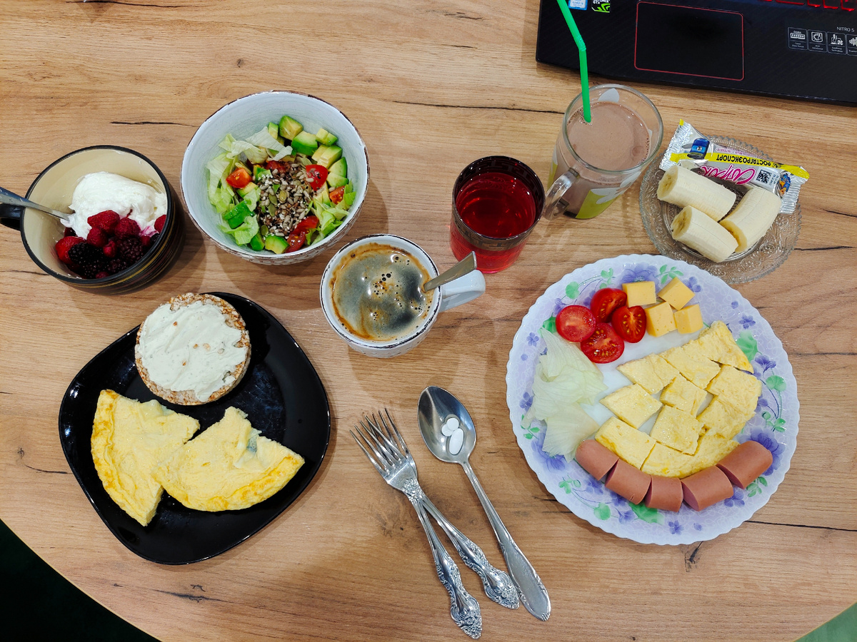 Слева мое: омлет, хлебец с творожным сыром, салат с авокадо, помидорами и семечками, творог с ягодами, кофе. Справа Адама: омлет, сыр, сосиска, овощи, банан, глазированный сырок, какао, компот и таблетки