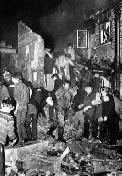 Спасатели, солдаты и гражданские копают голыми руками в ещё дымящихся руинах бара МакГурка на Норт-Куин-стрит в Белфасте