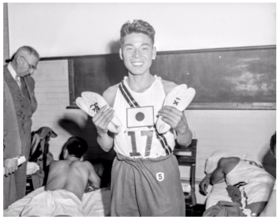 Шигеки Танака демонстрирует свои победные туфли «таби» с раздвоенным носком. Бостон, 1951.