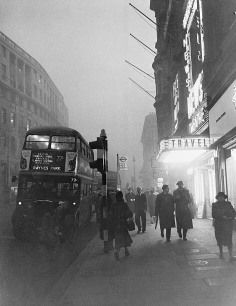 Пешеходы медленно идут сквозь дымку, которая почти полностью закрывает солнце.