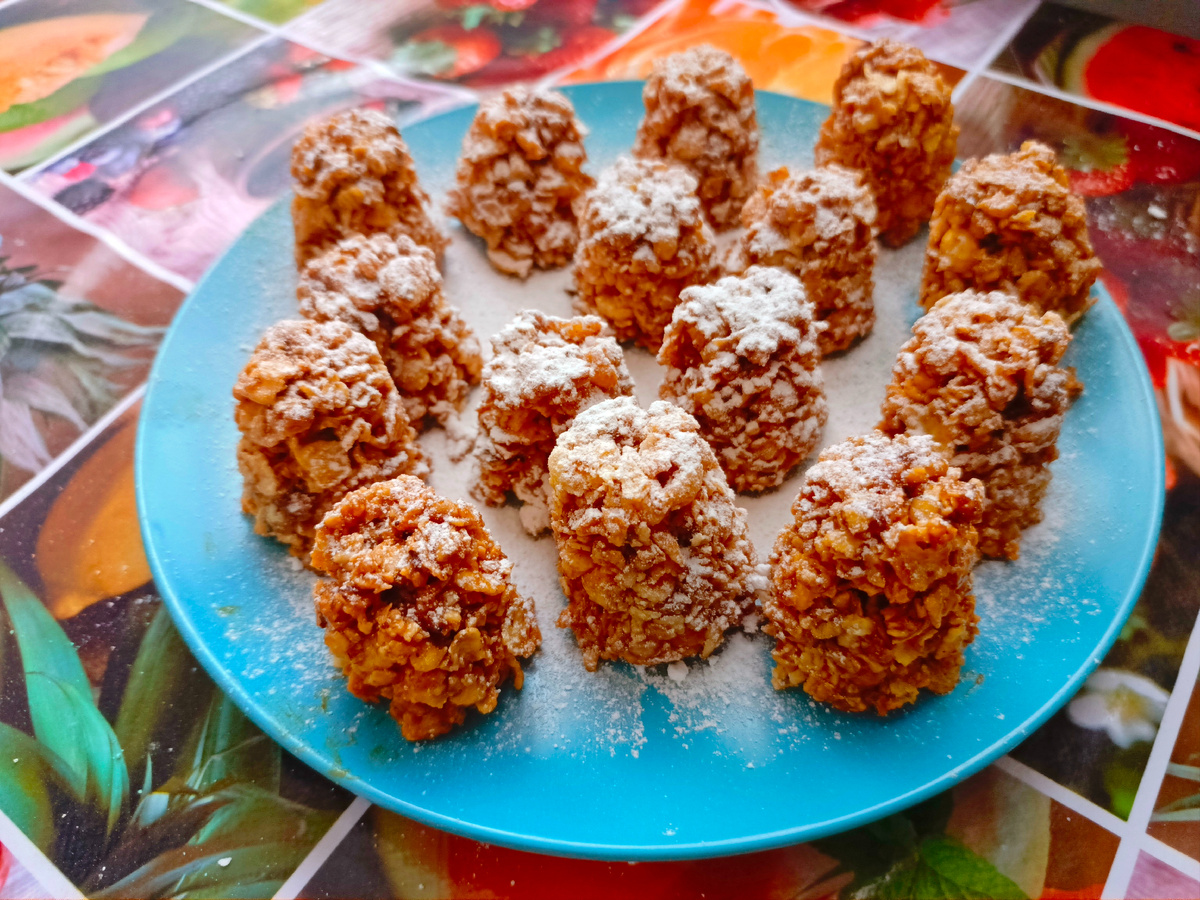 Всего из трех товаров - легко, скоро, просто, торжественно! Новогодний десерт без выпечки из кукурузных хлопьев со сгущенным молоком и орешками как испещренных снегом шишек украсит торжественный стол в новогодние празднички. 