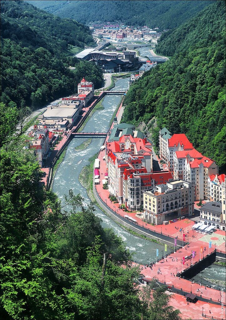 Вид на Красную Поляну, вытянувшуюся вдоль горной реки Мзымты. Вдалеке видно здание железнодорожного вокзала, а на переднем плане - построенные к олимпиаде отели. Фото из интернета.