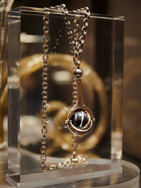 Ожерелье-подвеска Pluton из золота, серебра и бриллиантов от Elie Top открывается, чтобы показать ониксовый шар. На серии фотографий вверху ювелир развлекается в своем парижском выставочном зале и студии.