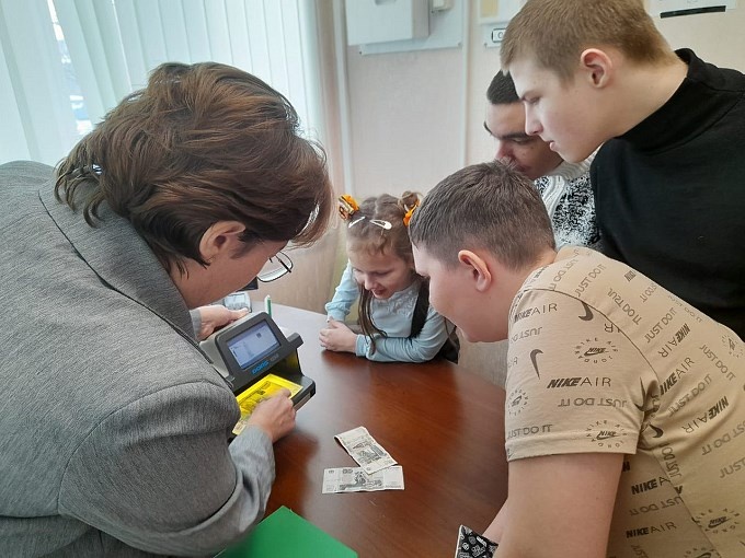 Руководитель офиса Сбербанка показывает детям работу машины для счёта купюр