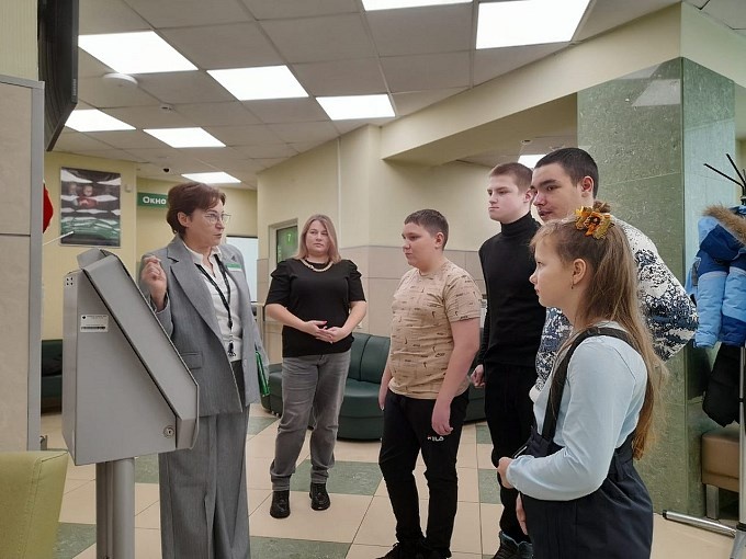 Руководитель офиса Сбербанка показывает детям работу электронной очереди