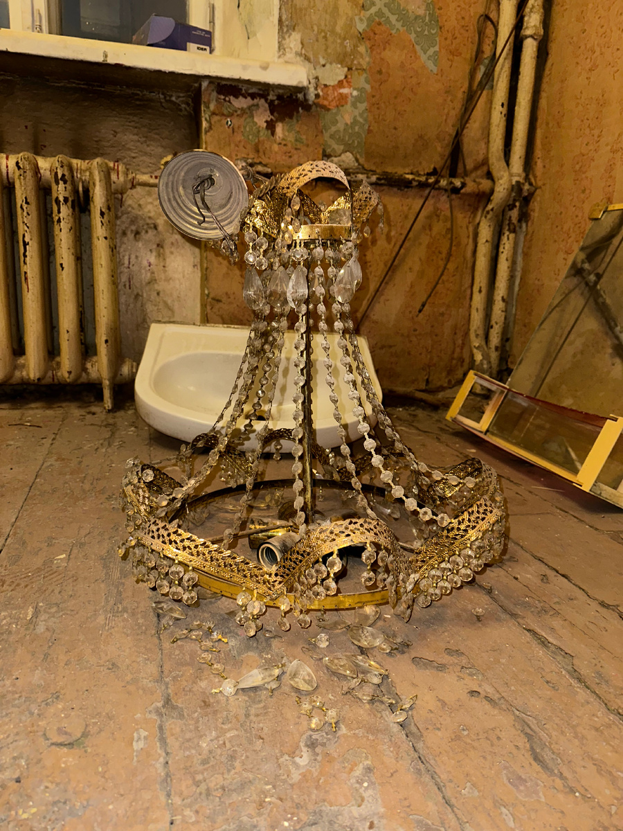 Крупный план потускневших хрустальных элементов винтажной люстры перед очисткой, отражающий этап подготовки к обновлению интерьера.