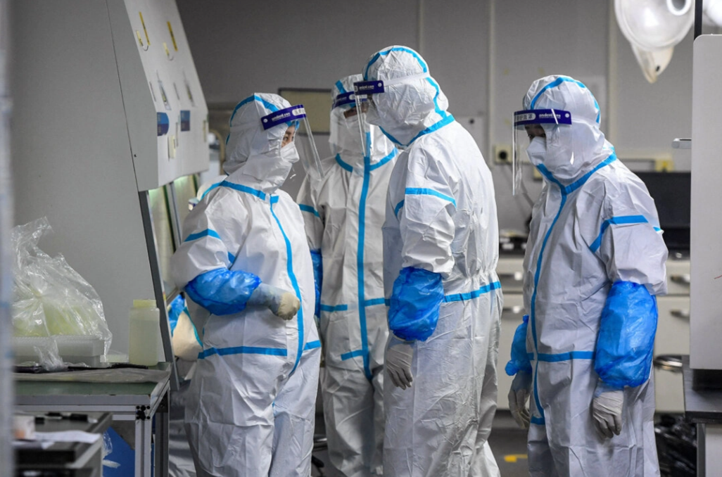 Лаборанты в средствах индивидуальной защиты работают с образцами для тестирования на COVID-19 в лаборатории Fire Eye, испытательном центре COVID-19, в Ухане, провинция Хубэй, Китай, 4 августа 2021 года. STR/AFP через Getty Images
