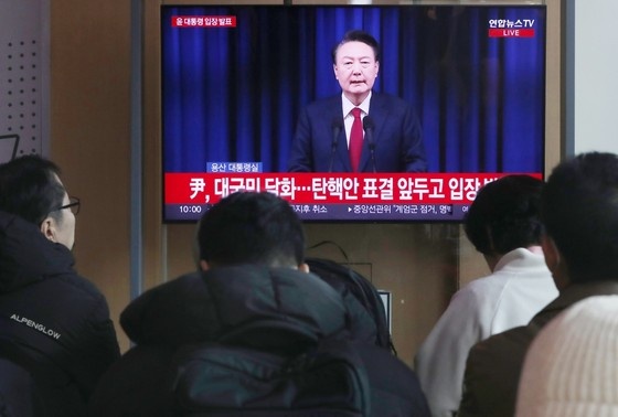    Люди смотрят телевизионное обращение президента Южной Кореи Юн Сок Ёля
