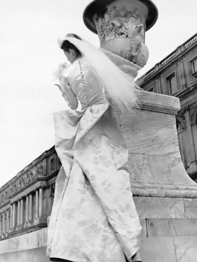 Модель в красивом парчовом атласном свадебном платье, напоминающем по форме тело бабочки, гладком спереди и расправленном сзади, как крылья, от Молинье, фотография Луизы Даль-Вульф в Версале, Harper's Bazaar, октябрь 1946 г.
