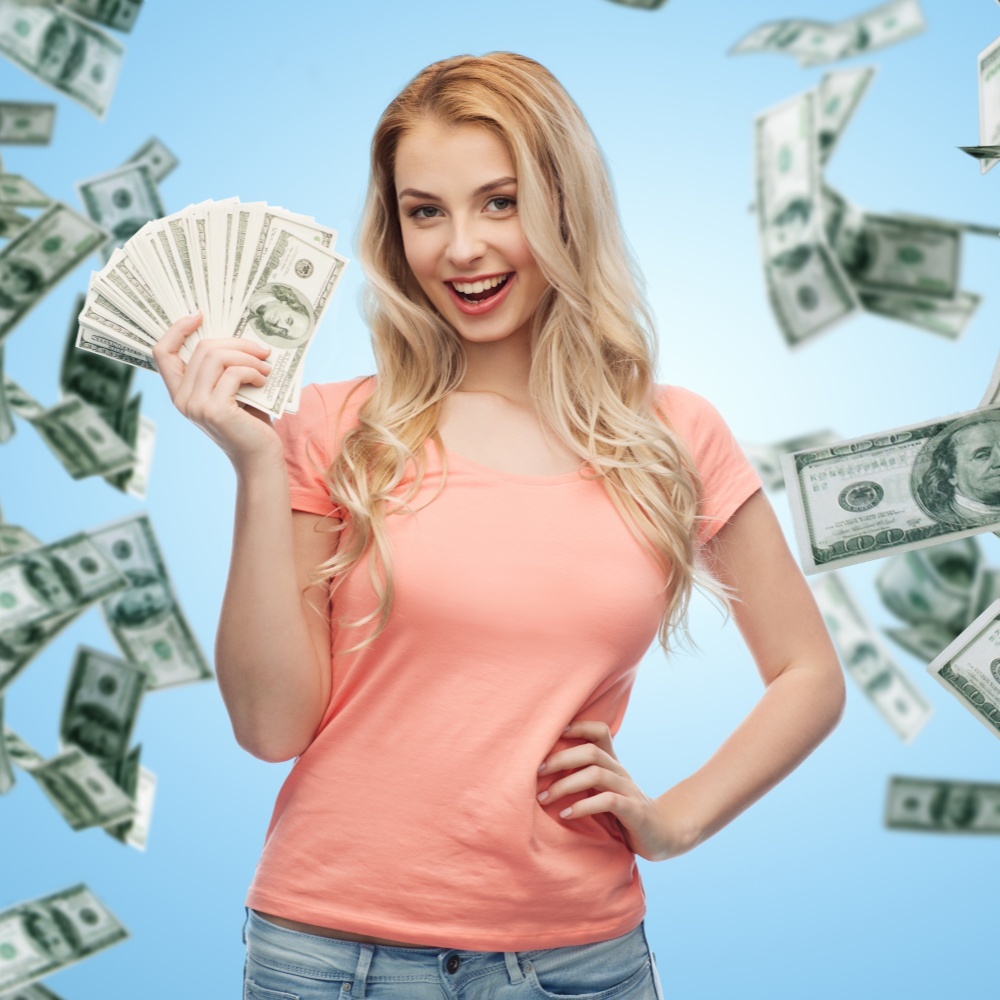    money, finances, investment, saving and people concept - happy young woman with dollar cash over money rain and blue background Leningrad