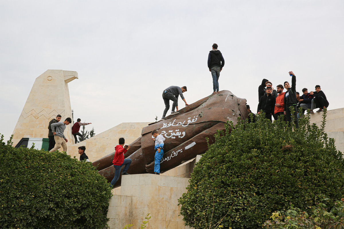 Люди на снесенной статуе бывшего президента Сирии Хафеза аль-Асада в Хаме после захвата города повстанцами, Сирия, 7 декабря 2024 года    📷