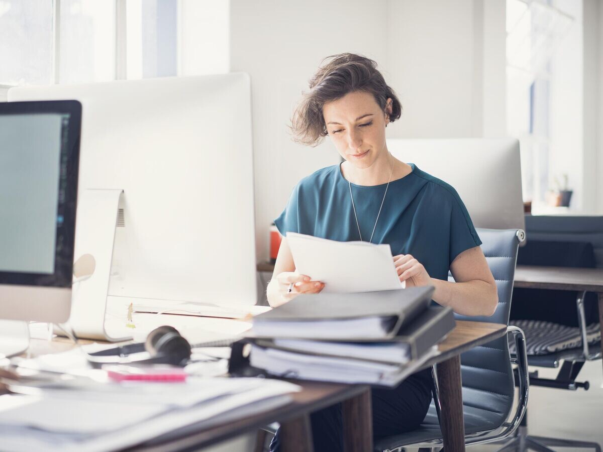    Девушка проверяет документы в офисе© Getty Images / Portra