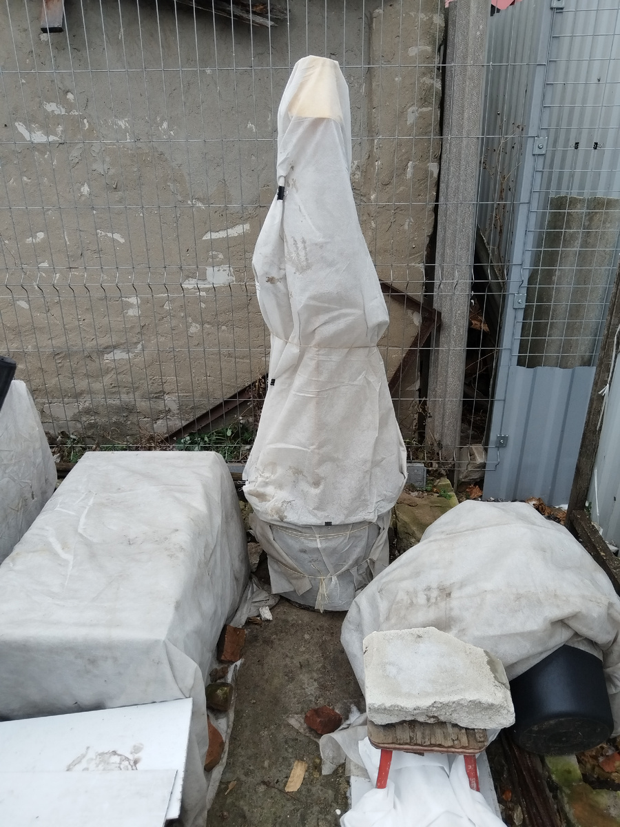 Сборище мумий у саркофага))) Слева под укрытием сидят горшки с многолетниками, справа - виноград и лилейники в ведрах, а вот это шедевральное мумиеподобное - это яблоня сахалинская в большом горшке, укрытая не от морозов, а от осадков