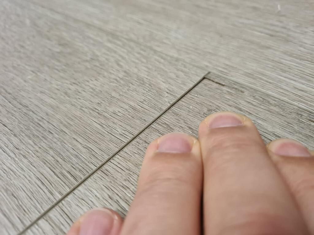 НА фото виден слом торцевого замква кварцвинила из-за неправильно выбранной подложки