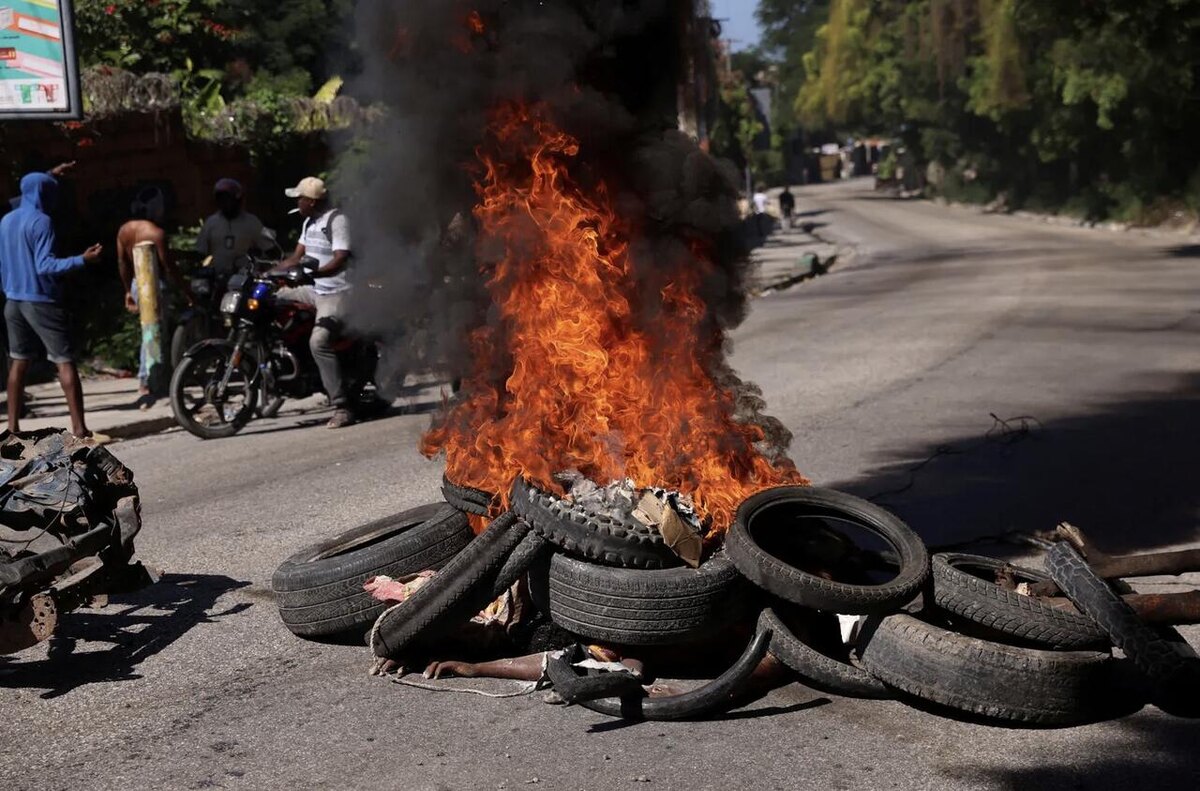 Тело частично видно под горящими шинами на улице Порт-о-Пренса.