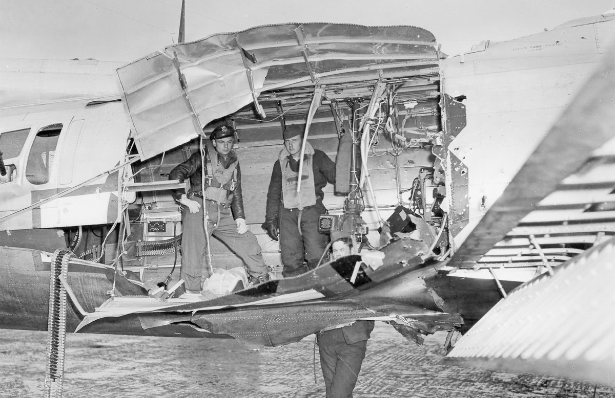 Американские летчики 2-й лейтенант Уинфилд Маффетт, сержант Уолтер Ингисон и сержант Джеймс Пирс из 508-й бомбардировочной эскадрильи 351-й бомбардировочной авиагруппы фотографируются в пробоине, образовавшейся в фюзеляже их самолета B-17G "Летающая крепость" в результате прямого попадания германского зенитного снаряда. Англия, графство Нортхэмптоншир, аэродром Полбрук, 27 сентября 1944 года.
