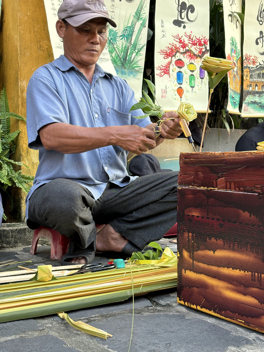 Местынй продавец-умелец делает розочки из бамбука.