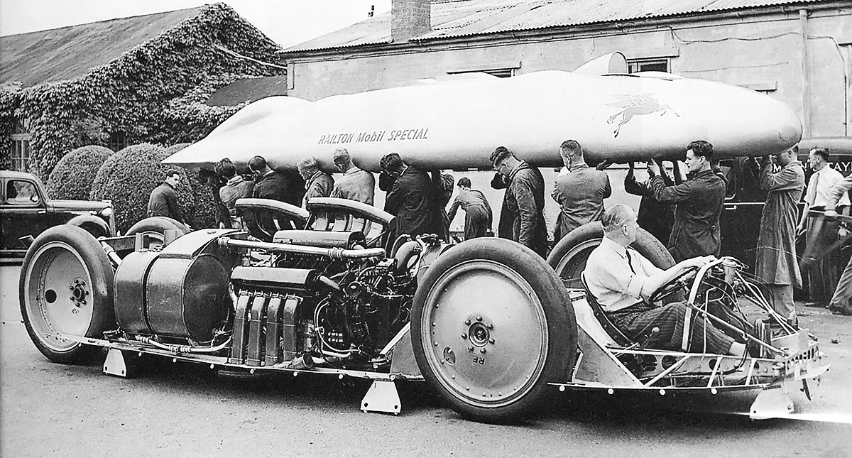 хотя кузов автомобиля Railton Special могли нести шесть человек, эту легкую работу выполняет гораздо большее количество людей. Масляный бак находится непосредственно перед задним колесом, за ним следуют перемещенный (в 1939 году) водяной и напорный баки. На защитном экране, прикрывавшем автомобиль снизу, можно увидеть множество замков Дзуса, использовавшихся для крепления кузова. Обратите внимание на вынесенную далеко вперед кабину водителя
