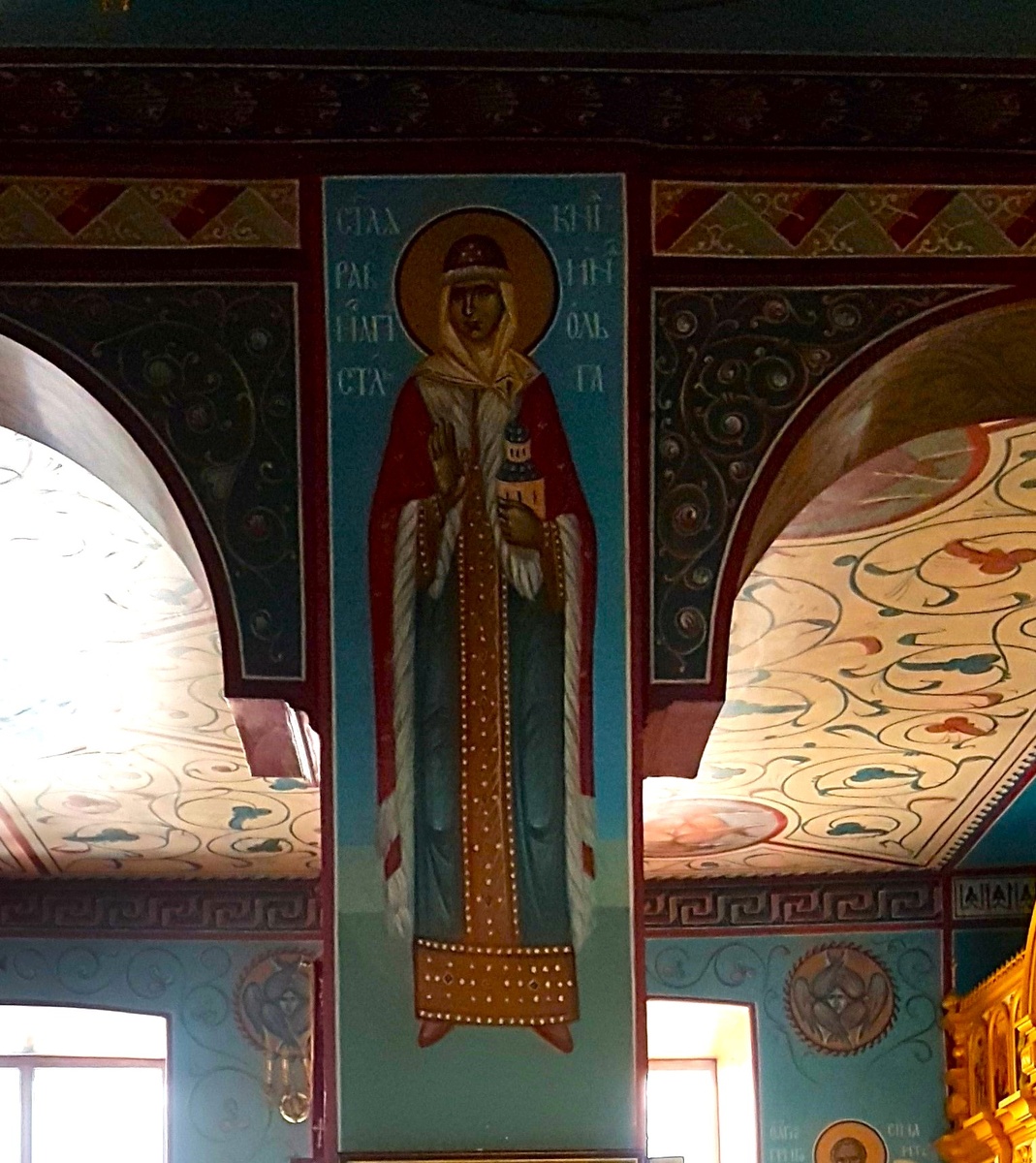 Роспись "Святая равноапостольная княгиня Ольга" на колонне придела преподобного Серафима Саровского, над иконой блаженного Лаврентия Калужского. Храм Успения Пресвятой Богородицы "за верхом" г. Калуга. На росписи равноапостольная великая княгиня Ольга изображена стоящей; на левой руке княгини изображен храм; это – отсылка к возведенному по повелению княгини Троицкому собору Пскова, но также – свидетельство того, что княгиня строила на Руси и другие храмы, распространяя веру. Одежды святой – княжеские; княгиня, облачена в русские княжеские одежды, в традиционной для княгини шапке. Одежды святой имеют красные и голубые цвета, которые являются символами власти и Царства Небесного.