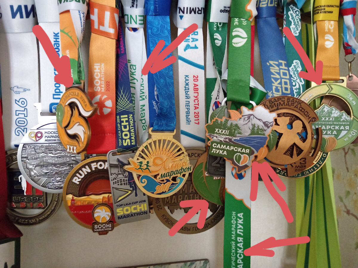 Мои медали за участие в марафонах. За участие в полумарафонах в этой куче медалей нет. Стрелочками обозначила медали с финиша марафона "Самарская Лука" в разные годы. 