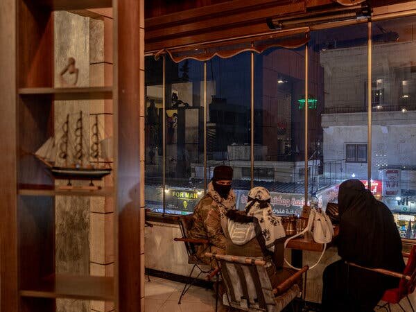 Боевик-повстанец с двумя женщинами в семейном отделе кафе «Шабабек» в Идлибе.Изображение