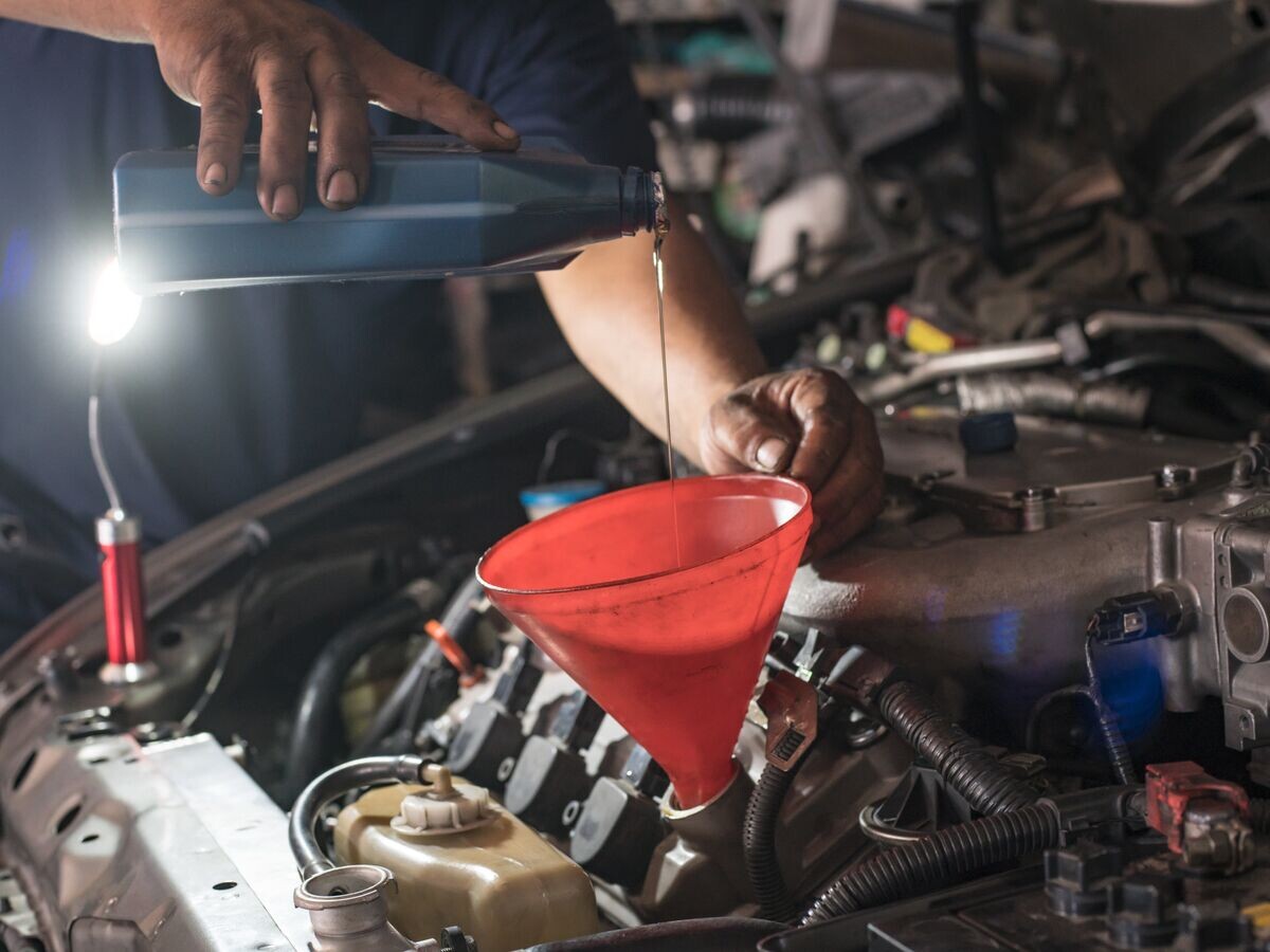    Мужчина заливает масло в двигатель автомобиля© Fotolia / Witthaya