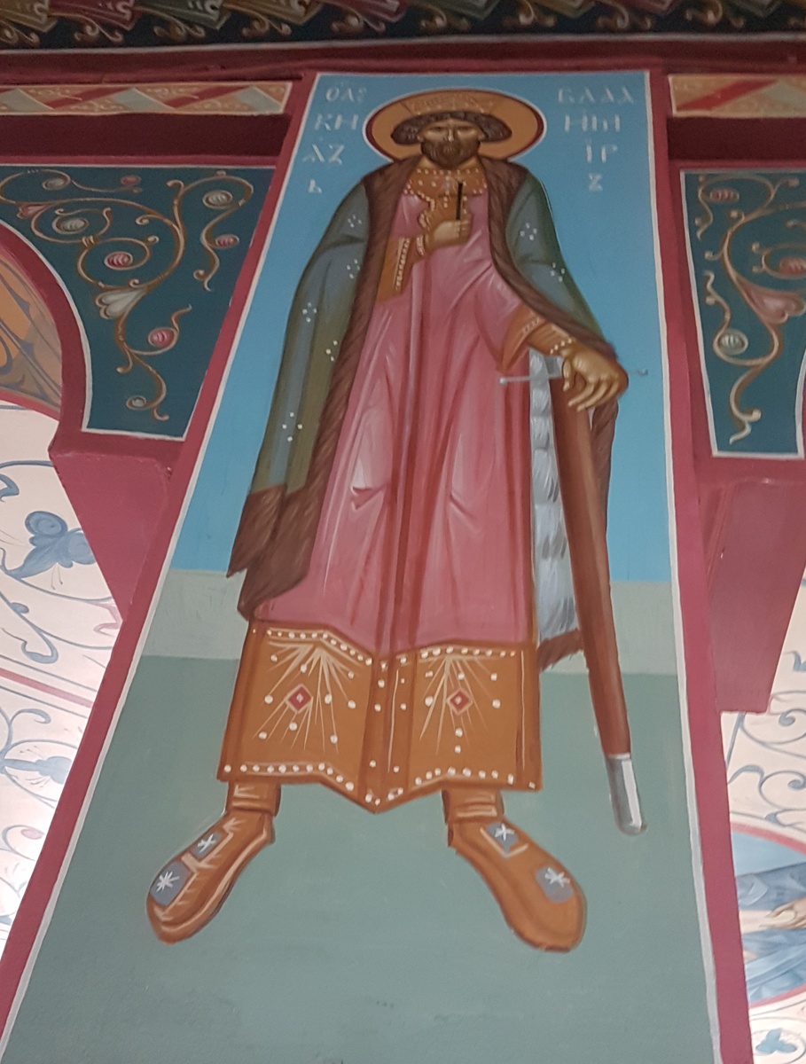 Роспись "Святой князь Владимир" на колонне придела преподобного Серафима Саровского, над иконой преподобного Пафнутия Боровского. Храм Успения Пресвятой Богородицы "за верхом" г. Калуга. Равноапостольный князь Владимир в росписи изображен в рост в византийском украшенном платье, но поверх византийских одежд накинута, подбитая мехом ферязь с длинными рукавами — одежда, характерная для Руси того времени. В правой деснице мудрого правителя Руси располагается крест, отсылающий к суждению о том, что в основании государства стоит православная вера. Левая рука прижата к телу, это говорит о покорности воле Господа, а меч, как символ надежной защиты государства, при помощи которого он прогнал врагов из Отечества. На голове Владимира — золотая корона, которую русские князья не носили, но уподобляет его византийским императорам. 